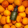 L'Arbre de paix Douceur d'Abricot signature oil in a dark green glass dropper bottle nestled among fresh apricots.