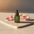 L'Arbre de paix Nuage de Rose signature oil in a frosted green glass dropper bottle with pink rose petals on marble