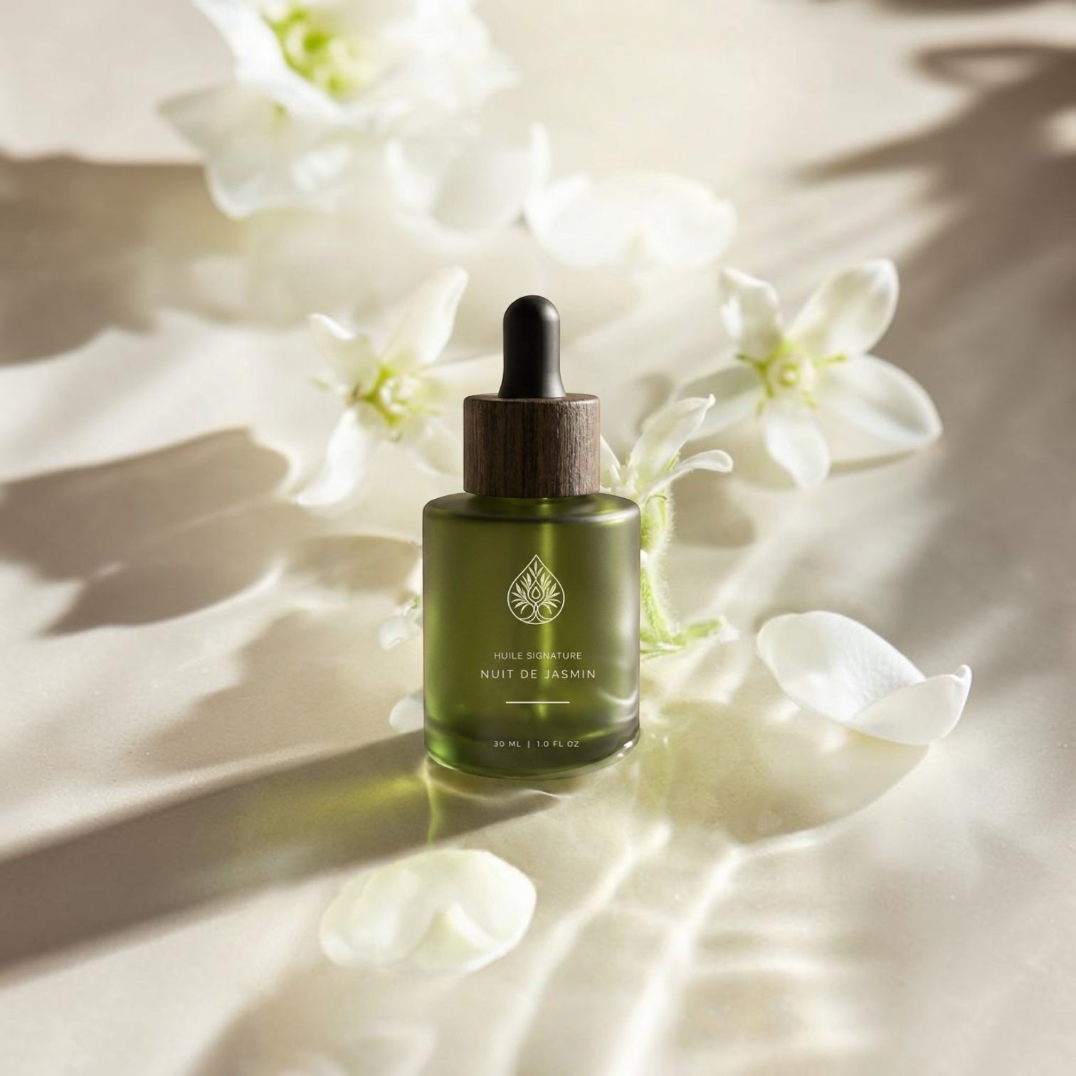 L'Arbre de paix Nuit de Jasmin signature oil in a green frosted glass bottle with a wooden dropper cap among petals.