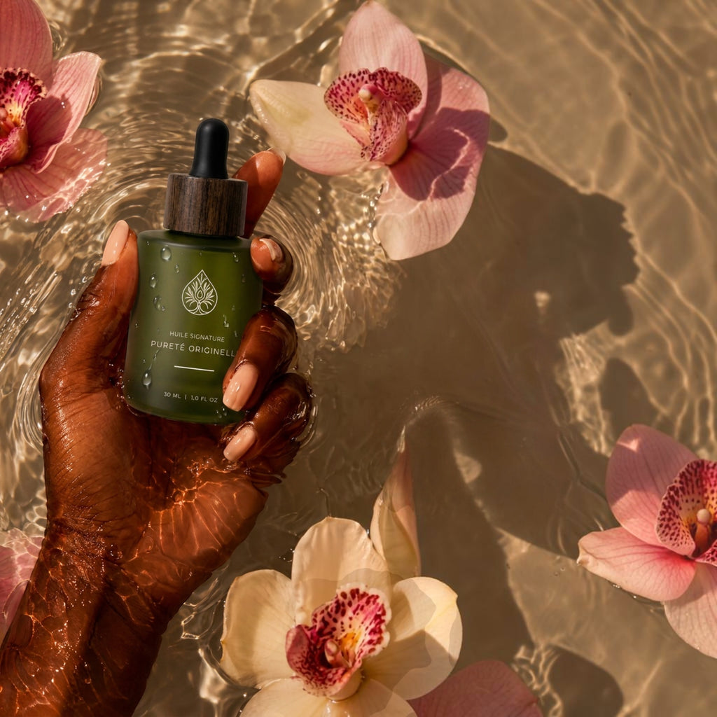 L'Arbre de paix Pureté Originelle signature oil in a green glass dropper bottle held in water with pink orchids